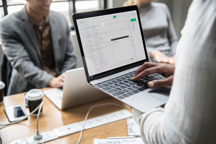 a person holding a laptop and typing in front of two persons